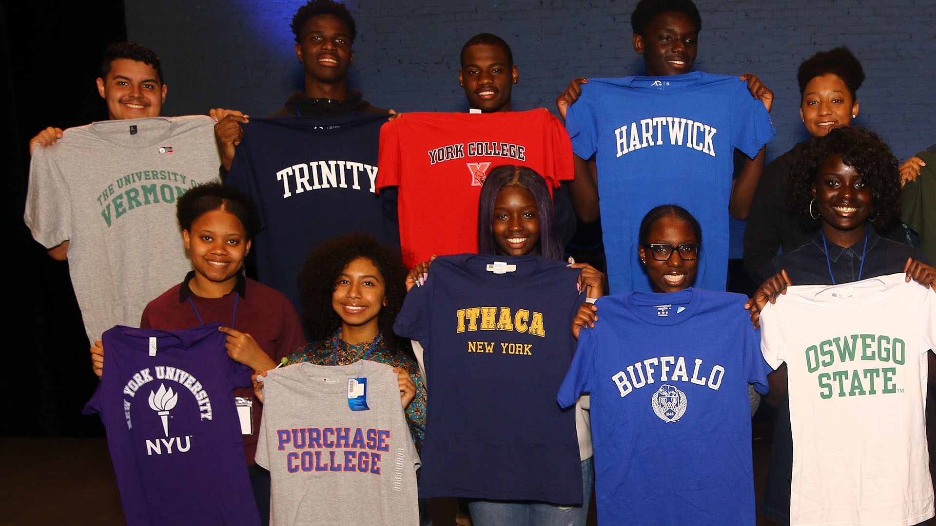 A group of HEAF students hold up their college shirts